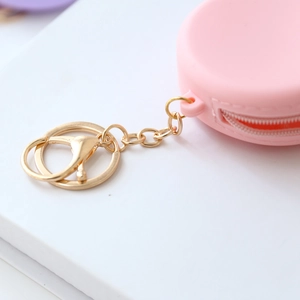 Detail of pink silicone macaron coin purse with gold zipper and metal keychain