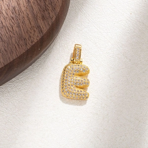 Macro shot of gold-plated letter E pendant with brilliant pave-set zircon crystals