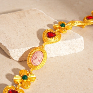 Vintage gold-tone bracelet featuring pink cameo, red heart and green floral accents