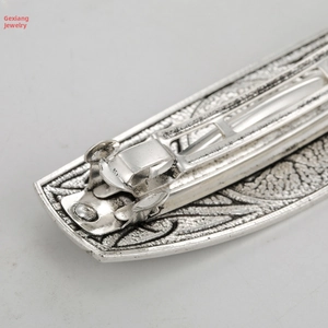 Detail view of vintage silver hair clip showing relief patterns and metal spring fastener