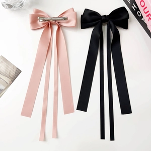 Close-up of pink and black satin bow hair clips with long ribbons and metal duckbill clips
