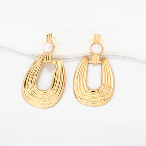 Detail of gold drop earrings featuring ribbed texture with elegant white pearls