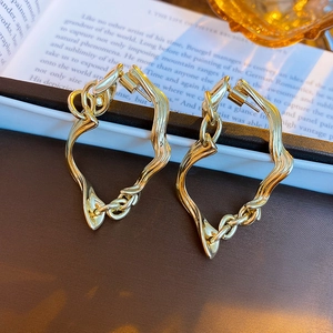 Detailed view of gold irregular geometric twist earrings on vintage box and book