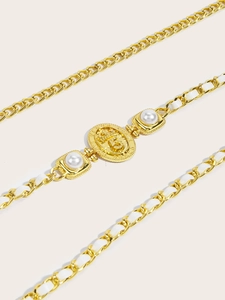Detail of gold metal waist chain with crown badge, pearls and white woven leather