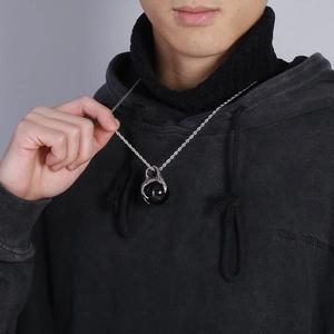 Detailed close-up of a dragon claw pendant holding a black orb on a silver chain necklace