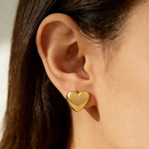 Polished 18k gold plated heart-shaped stainless steel earrings on a model’s ear