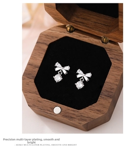 Close-up of S999 silver bow earrings with round cubic zirconia in a wooden jewelry box