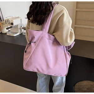 Detail of purple tote bag showing the side drawstring feature and lightweight texture