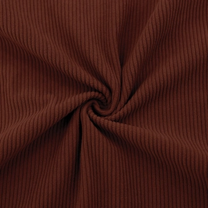 Macro detail of dark brown corduroy fabric showing soft vertical ribbed texture and soft lighting
