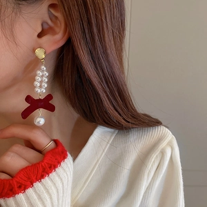 Detail of red velvet bow earrings with pearls shown on model for elegant style