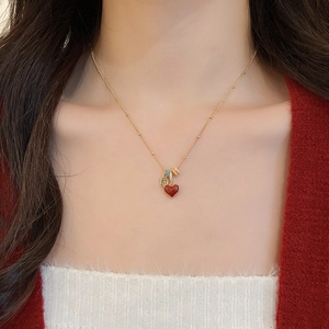 Close-up of 18k gold plated heart necklace with red pendant worn by a model