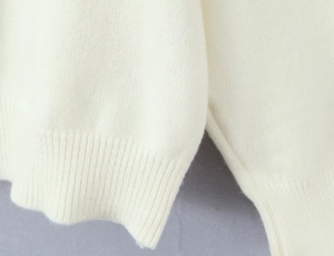 Detail of ribbed cuffs on an ivory white knit cardigan with fine knit texture