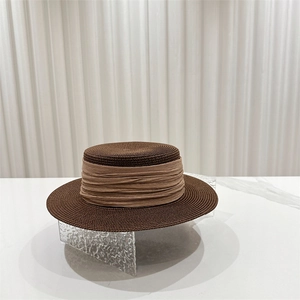 Detail view of woven straw boater hat with textured ribbon on a marble stand
