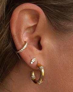 Gros plan de boucles d'oreilles bambou dorées et de bagues d'oreille en zircons blancs