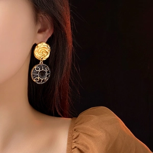 Vintage gold and black enamel round drop earrings worn by model with luxury aesthetic
