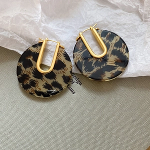 Detail of leopard print acrylic hoop earrings with gold-plated metal closure elements