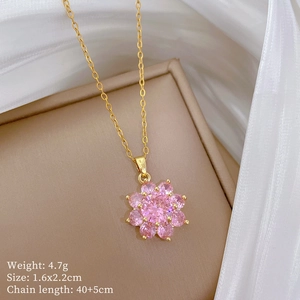 Close-up of sparkling pink zircon flower pendant with golden chain on silk fabric