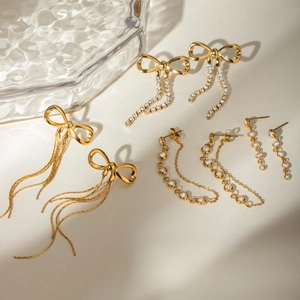 Golden bow tassel earring set with crystal rhinestones on a rippled glass tray