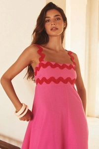 Detail of red zigzag shoulder straps and wave embroidery on a pink summer maxi dress
