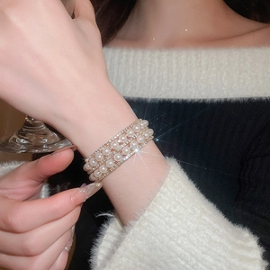 Detailed close-up of a triple-layer pearl bracelet with sparkling zircon accents on wrist
