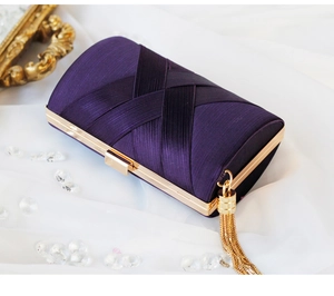 Detail of purple satin evening clutch with elegant gold fringe and luxury metal clasp
