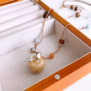 Detail of apple-shaped tiger eye pendant on a handmade beaded woven sweater chain