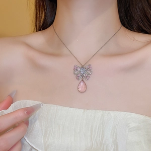 Detail of silver butterfly necklace with pink zircon and water drop pendant on neck