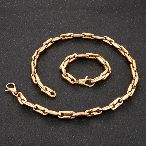 Detailed view of golden coffee bean link chain necklace and bracelet set on a black surface