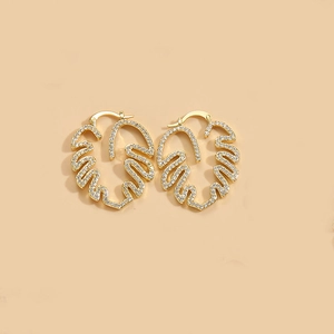 Macro shot of gold monstera leaf earrings featuring pavé cubic zirconia details