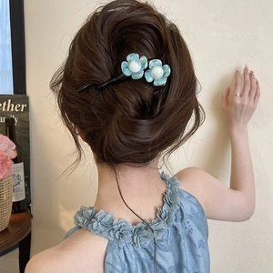 Detail of light blue resin flower hair clip with white faux pearls on model's hair