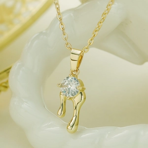 Gold plated lava droplet necklace with round zircon pendant on white ceramic base