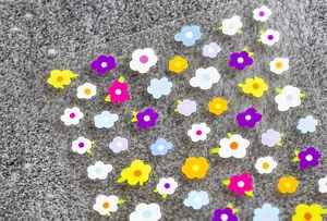 Vue macro détaillée de stickers à ongles fleurs 5D colorés sur support transparent