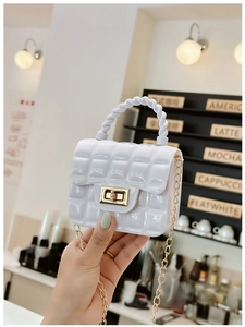 Detail of white quilted jelly bag with gold twist lock and spiral handle on a chain strap