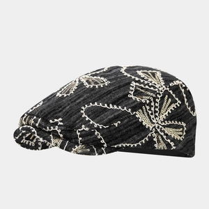 Detailed view of black denim hat with white embroidery and gold sequins flowers