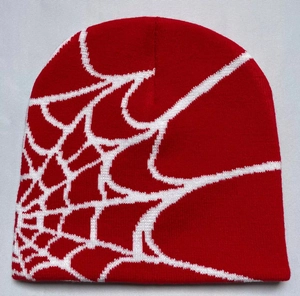Detail of red knit beanie featuring a white spider web jacquard pattern and tight texture