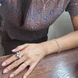 Detail of twisted silver bead ring and geometric chain bracelet on model wrist