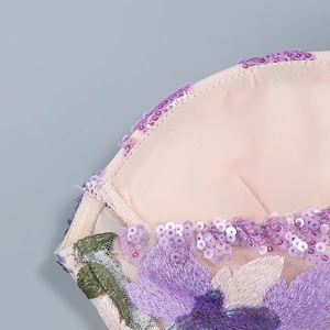 Macro detail of purple sequins and floral embroidery on beige mesh fabric dress
