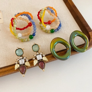 Macro detail of vintage glass flower earrings with beads and resin in wooden tray