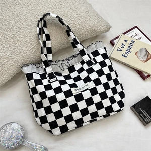 Close-up of black and white checkered canvas tote bag with lace trim and Korean text label