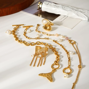 French style gold plated stainless steel bracelet and pearl ring set on white surface