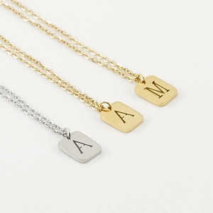 Detailed view of rectangular gold and silver initial pendants on delicate chain necklaces