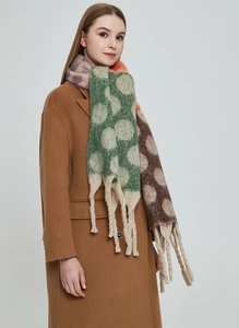 Dettaglio di sciarpa invernale spessa a pois con lunghe frange su un cappotto color cammello