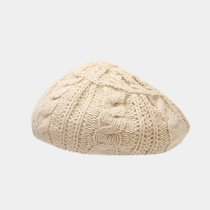 Close-up of cream white knit beret showing thick cable stitch texture for winter