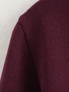 Detailaufnahme des weinroten Strickgewebes mit Textur und verstärkten Schulternähten
