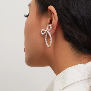 French bow tassel earrings with white pearls and gold accents shown on a model