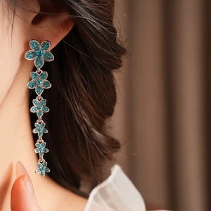 Gros plan de boucles d'oreilles fleurs en zircon bleu portées par un mannequin chic