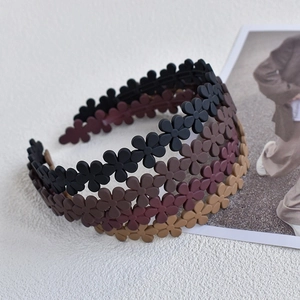 Close-up of four matte acrylic floral headbands in earthy tones on a white textured board