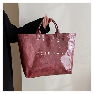 Macro shot of glossy burgundy tote bag with embossed texture and white TOTE BAG text