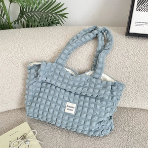 Close-up of sky blue bubble pleat fabric and square brand label on canvas tote bag