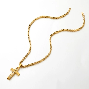 Makroaufnahme der goldenen Kreuzkette mit Zirkonia und geflochtener Kettenstruktur